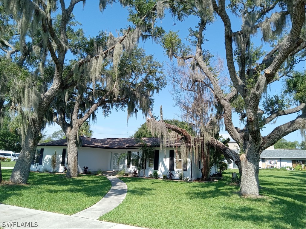 a view of a white house with a big yard and large trees