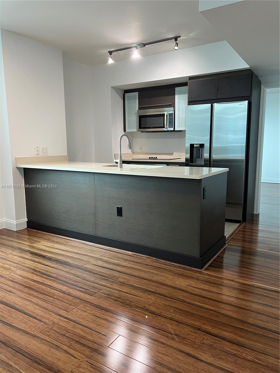 a view of kitchen with stainless steel appliances wooden floor and living room