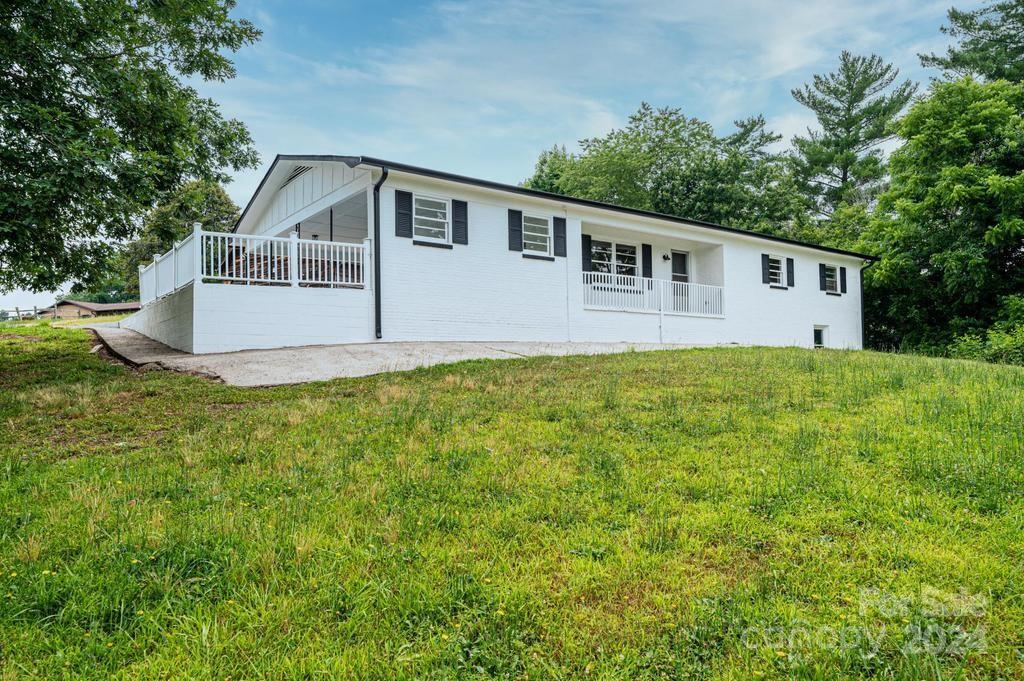 a house that is sitting in the grass with tress in the background