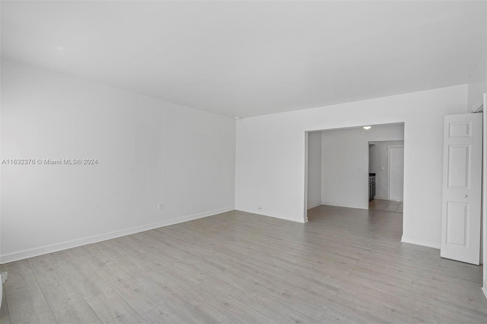 a view of an empty room with wooden floor and closet