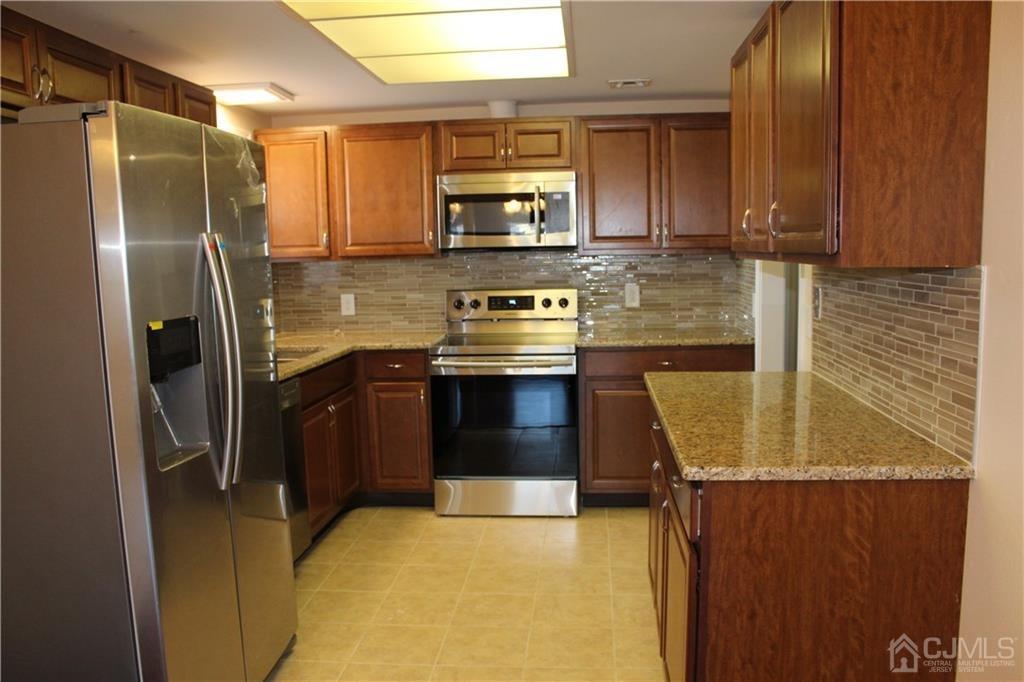 a kitchen with stainless steel appliances granite countertop a refrigerator a stove and a sink