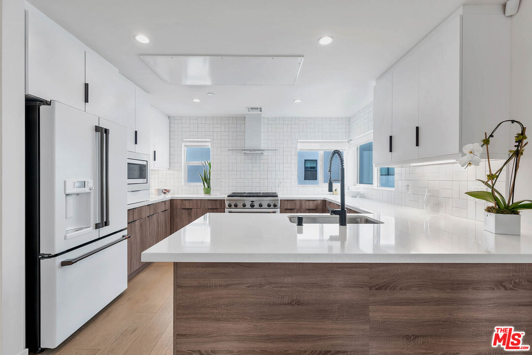 a kitchen with stainless steel appliances granite countertop a refrigerator and a sink