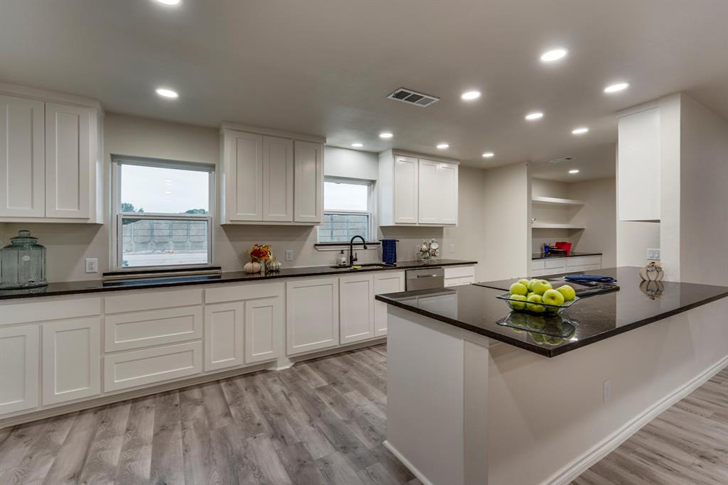 a kitchen with kitchen island granite countertop a sink a stove a counter space and a window