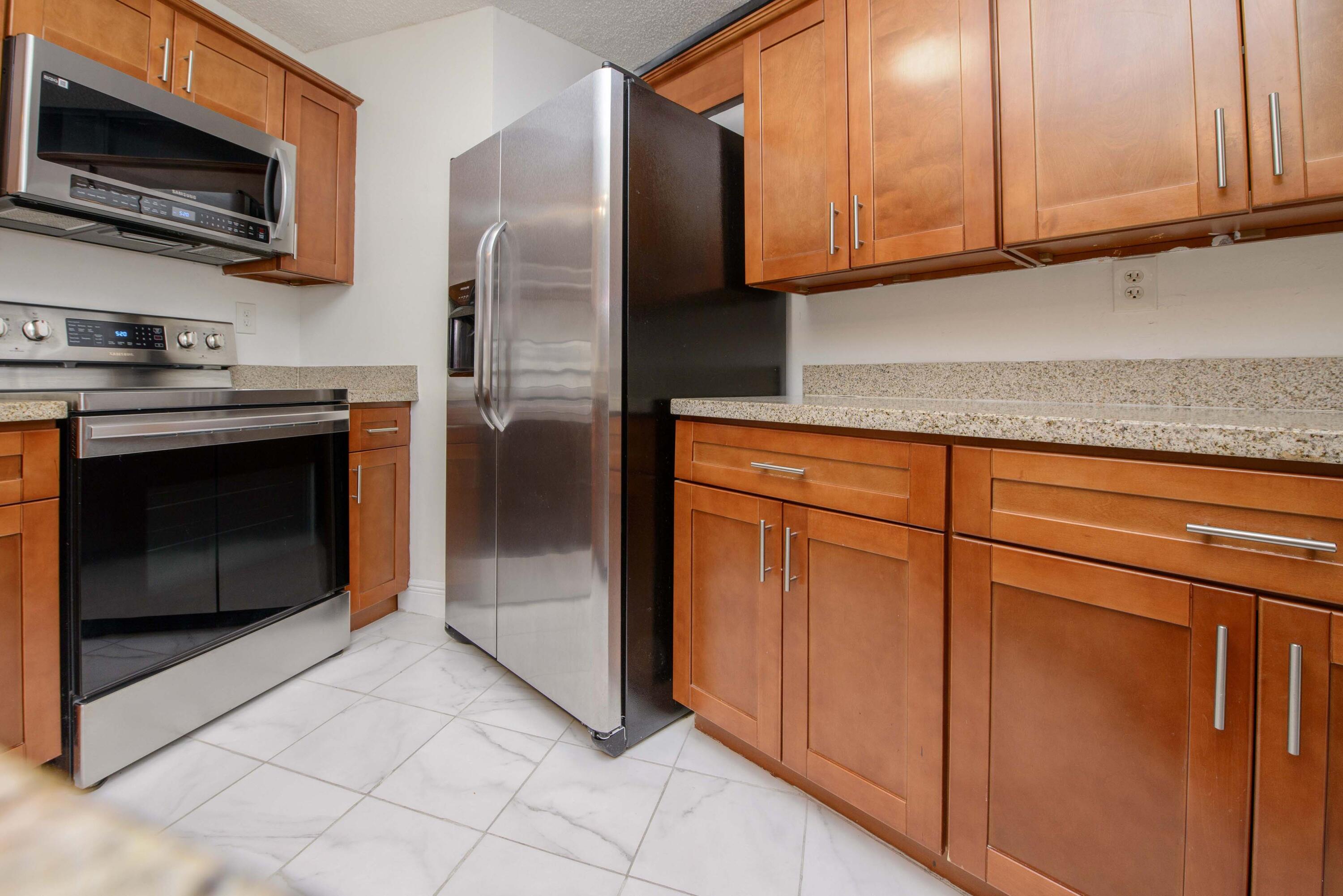 a kitchen with stainless steel appliances granite countertop a refrigerator stove and microwave