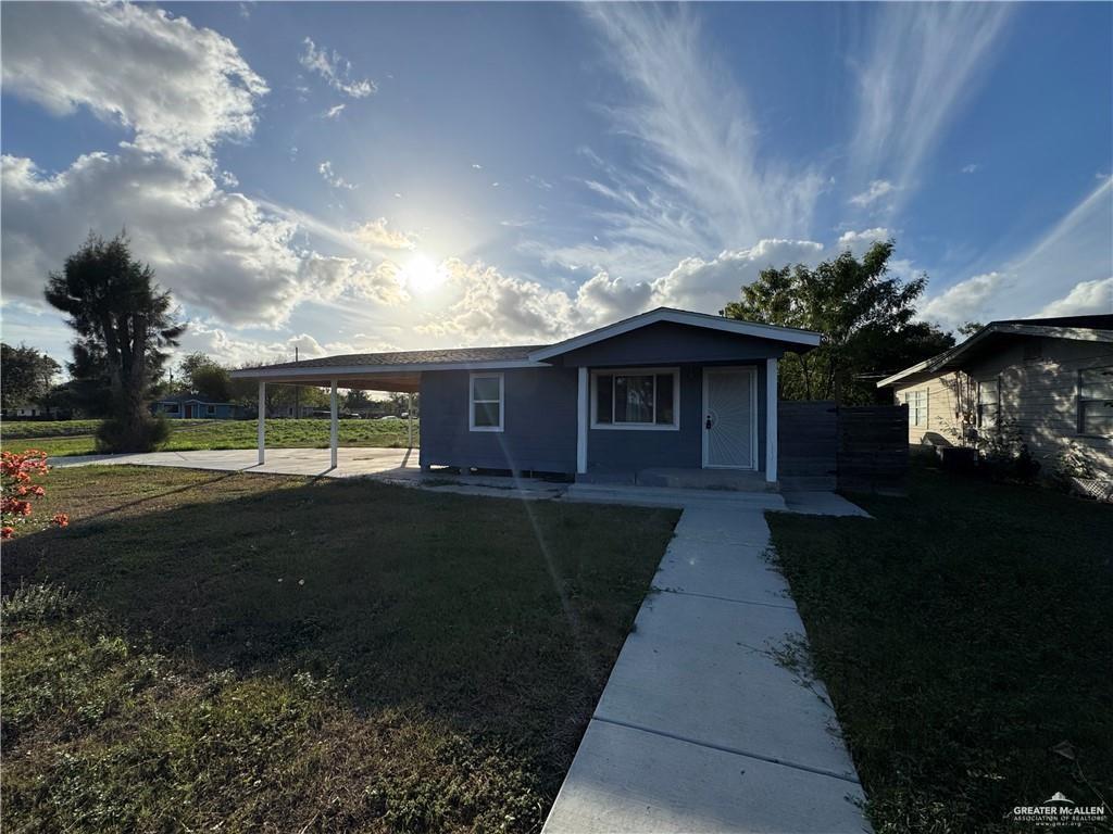 View of front of property featuring a front lawn and a carport