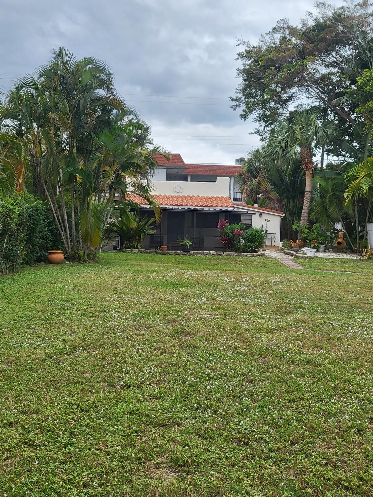 a view of a house with a big yard and large trees