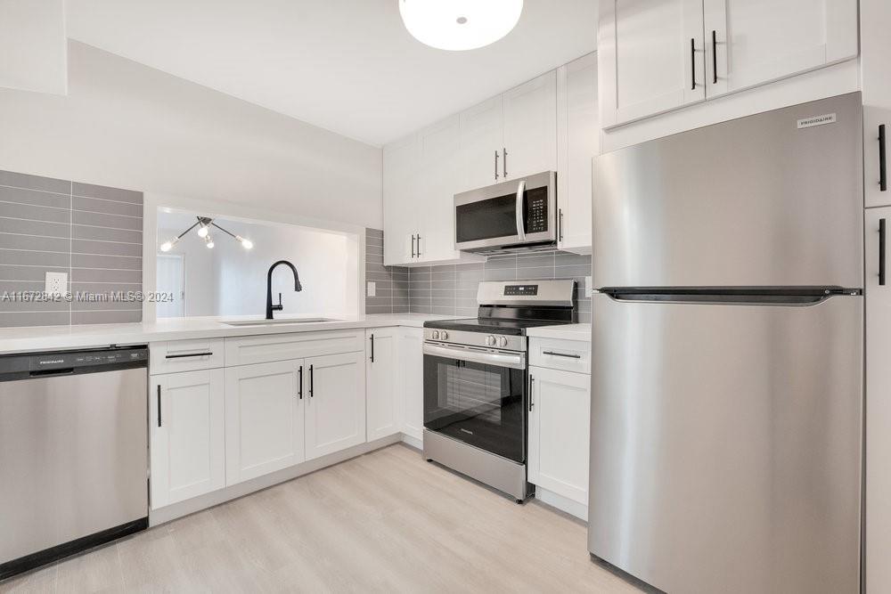 a kitchen with white cabinets and stainless steel appliances