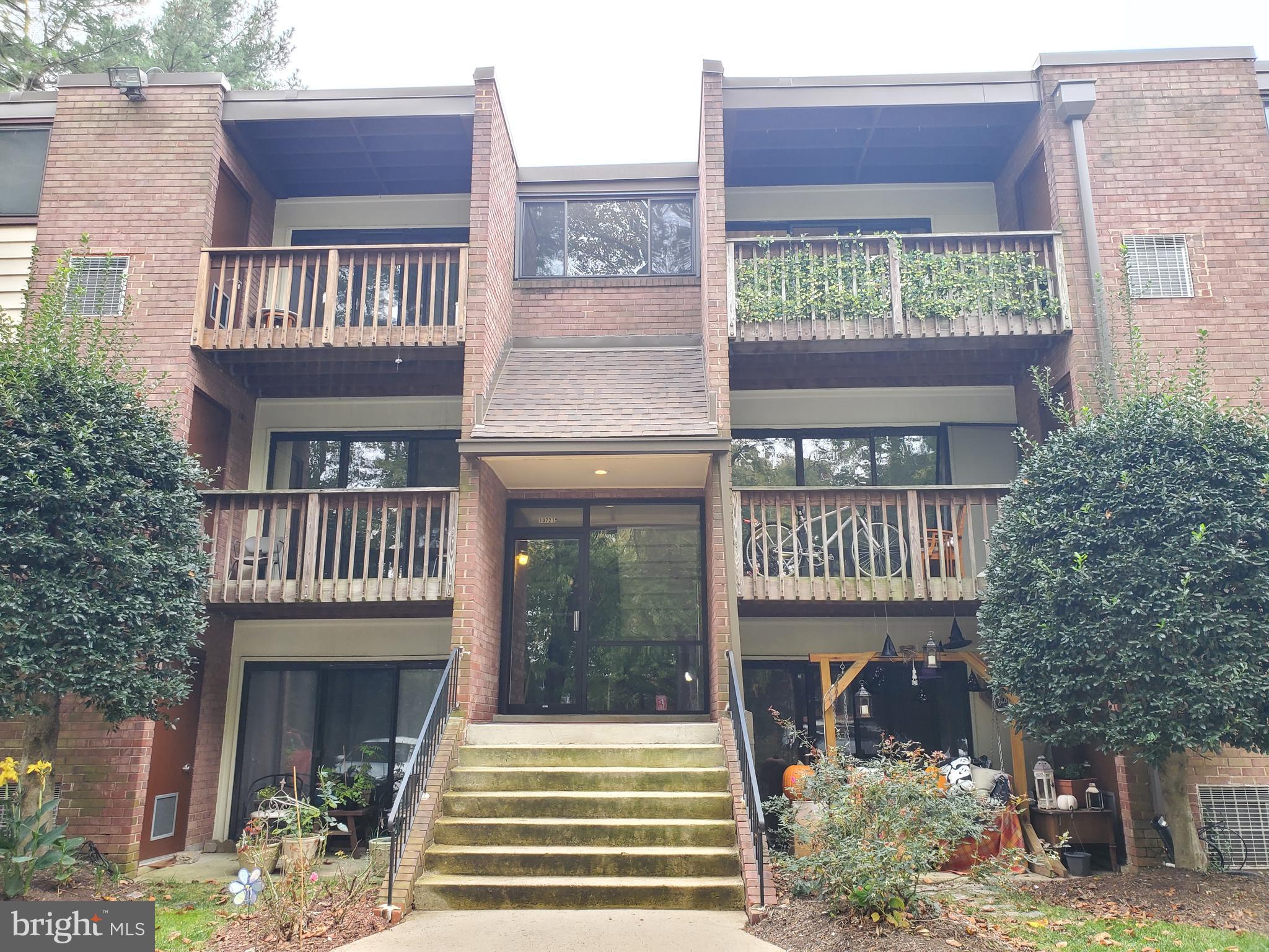 a view of a brick house with large windows and plants