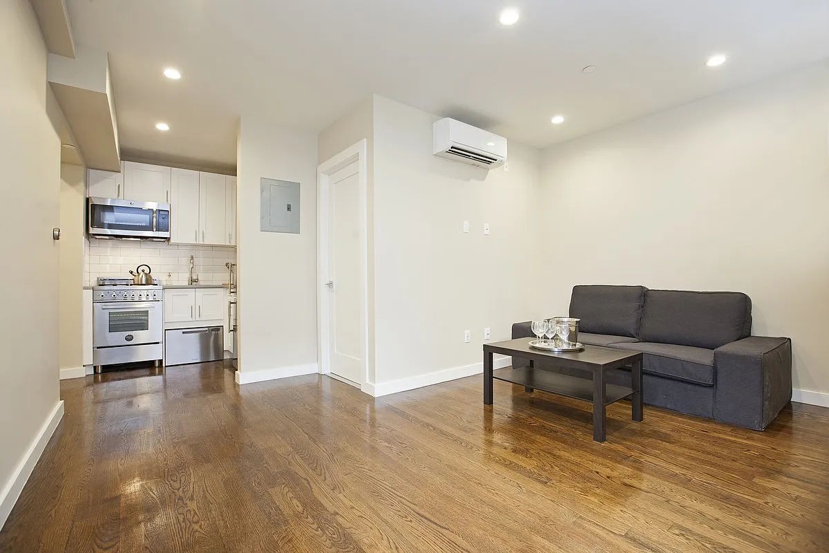 a living room with stainless steel appliances furniture and a kitchen view