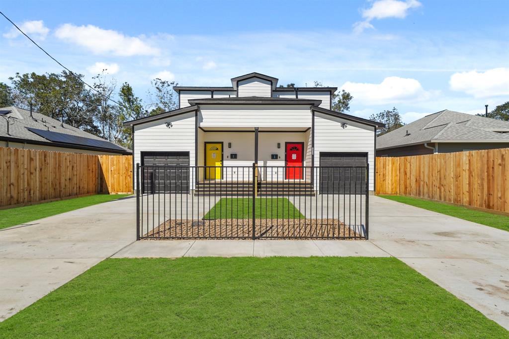 a view of a brick house with a small yard and a large parking space