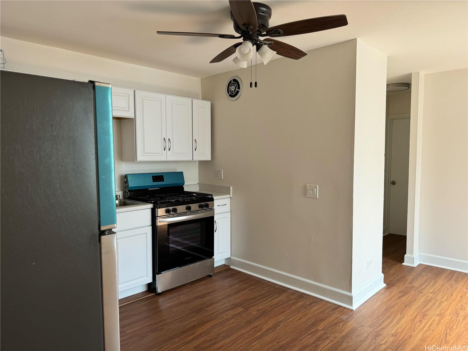 a kitchen with granite countertop a stove cabinets and wooden floor