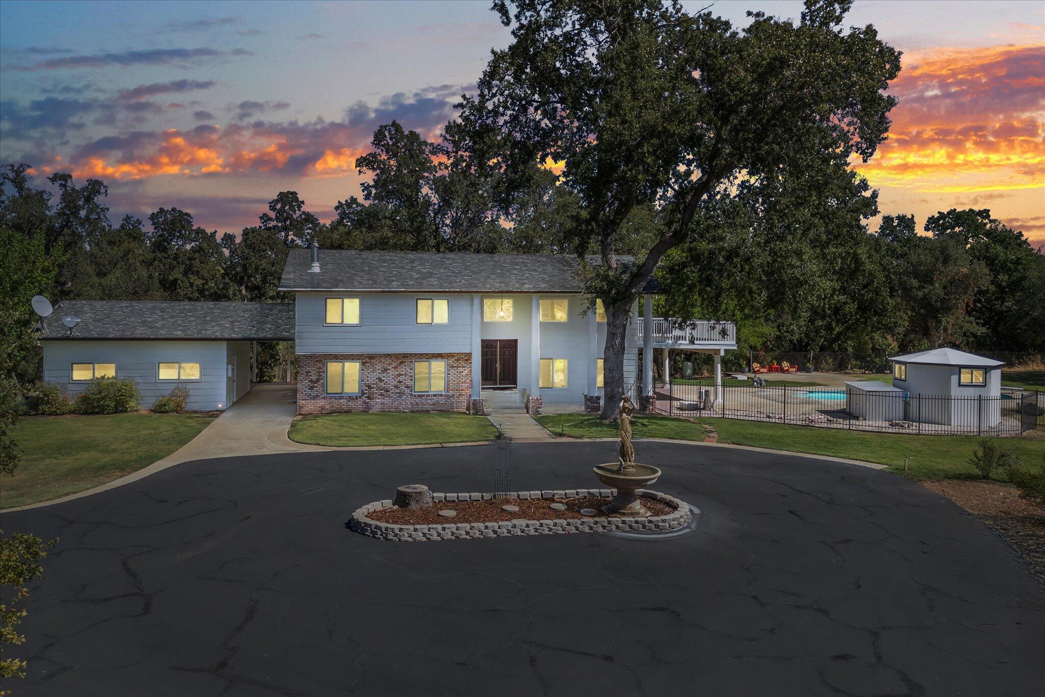 a view of a house with a yard fire pit and a large tree