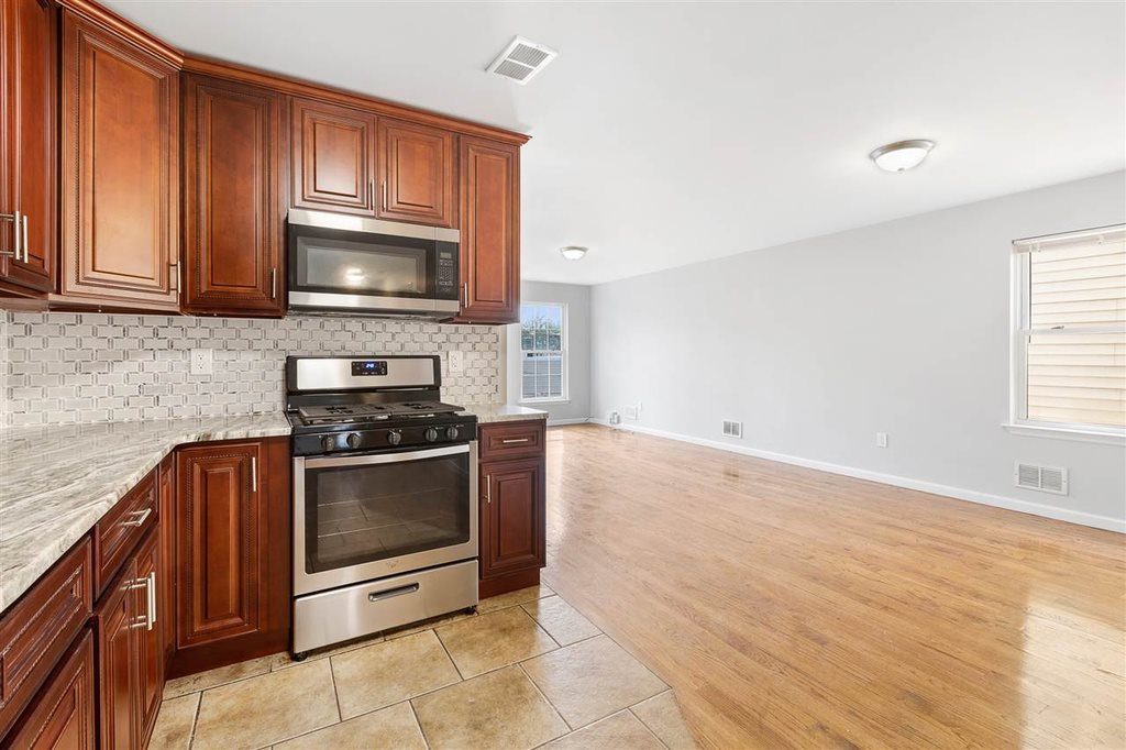 a kitchen with granite countertop a stove top oven microwave and cabinets