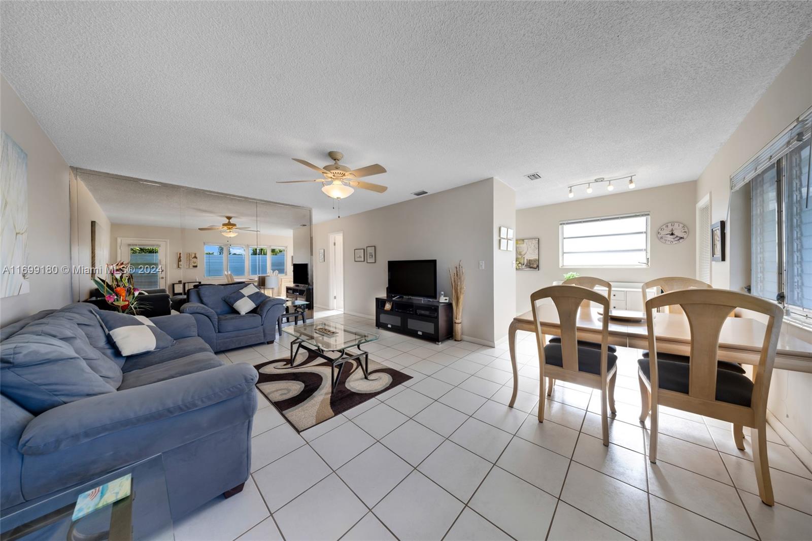 a living room with furniture a flat screen tv and kitchen view