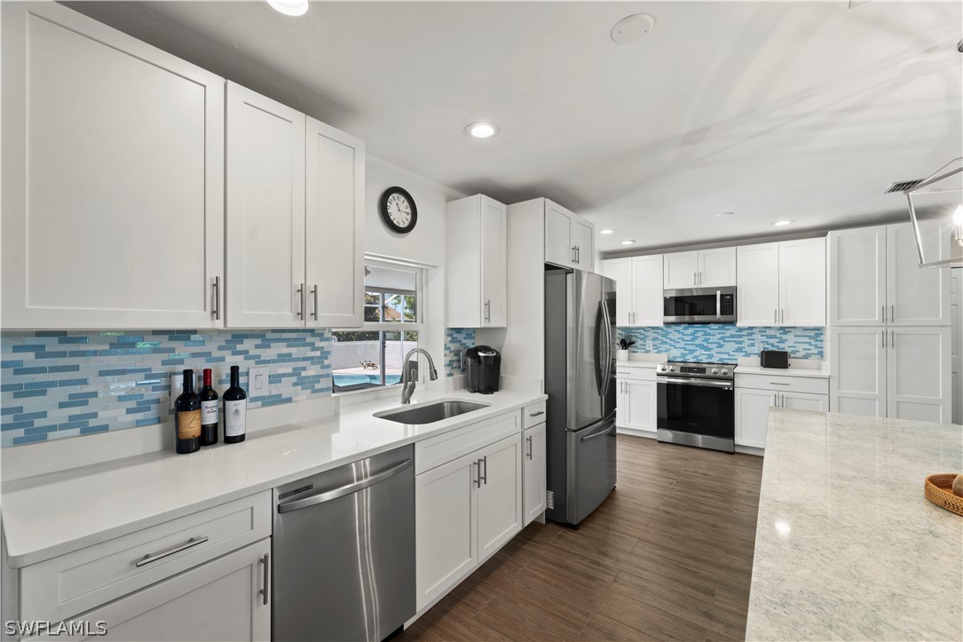 a kitchen with a sink cabinets stainless steel appliances and a window