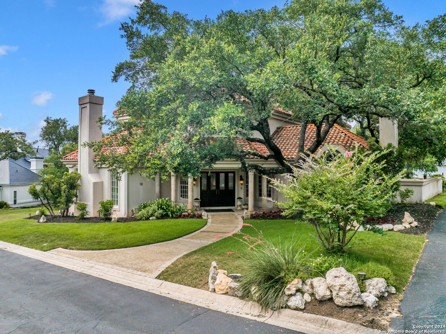 a front view of a house with a garden and trees