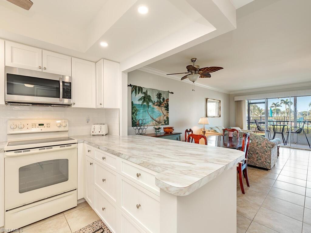 a view of living room kitchen with stainless steel appliances cabinets and flat screen tv