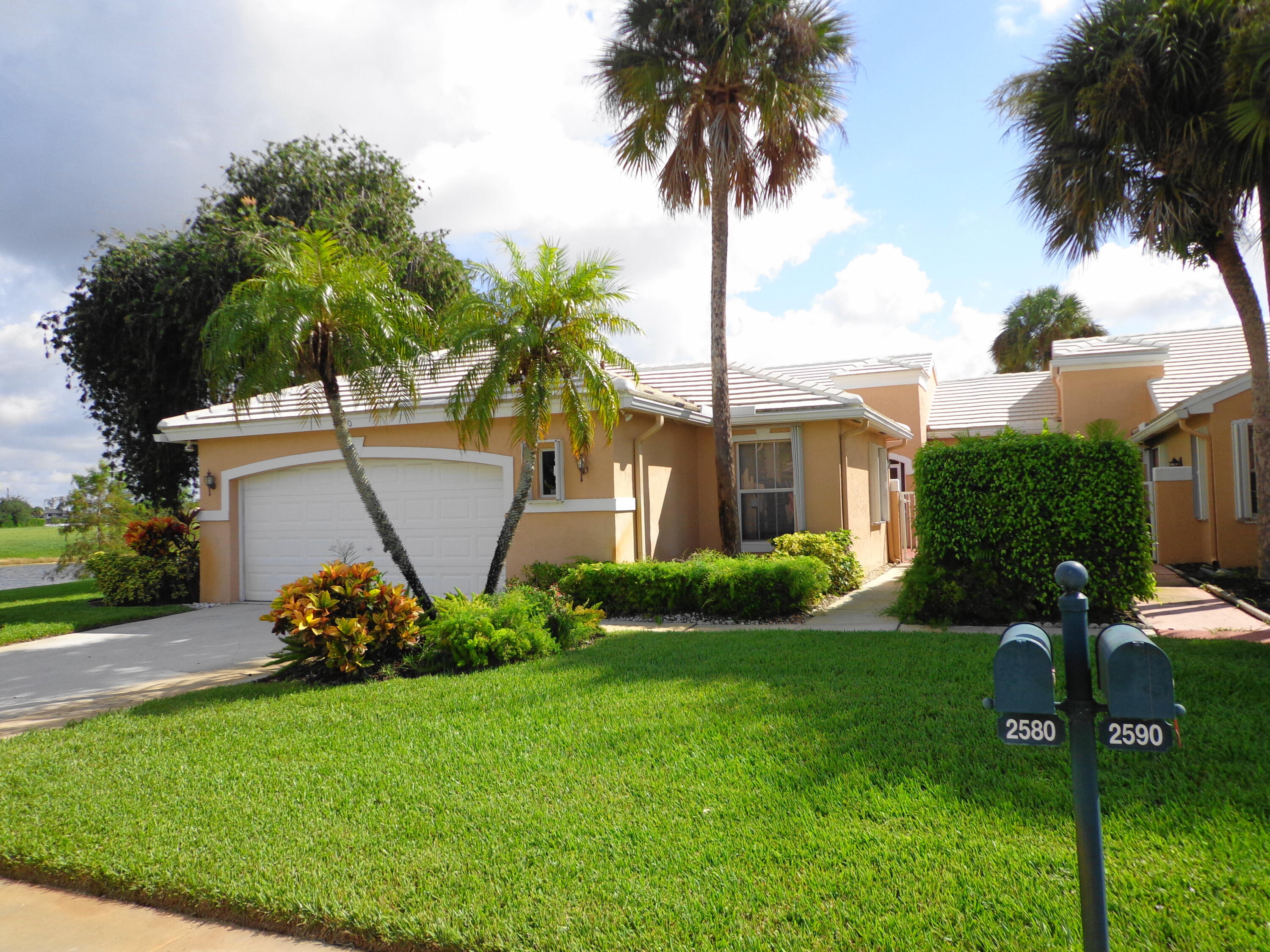 a front view of a house with garden and trees