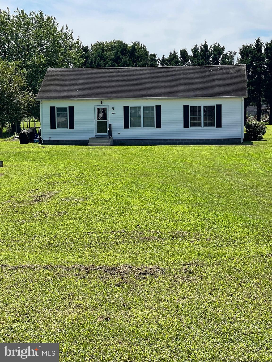 a house that has a big yard with plants and trees in the background