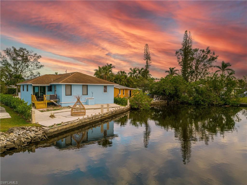 Back house at dusk featuring a water view and a patio