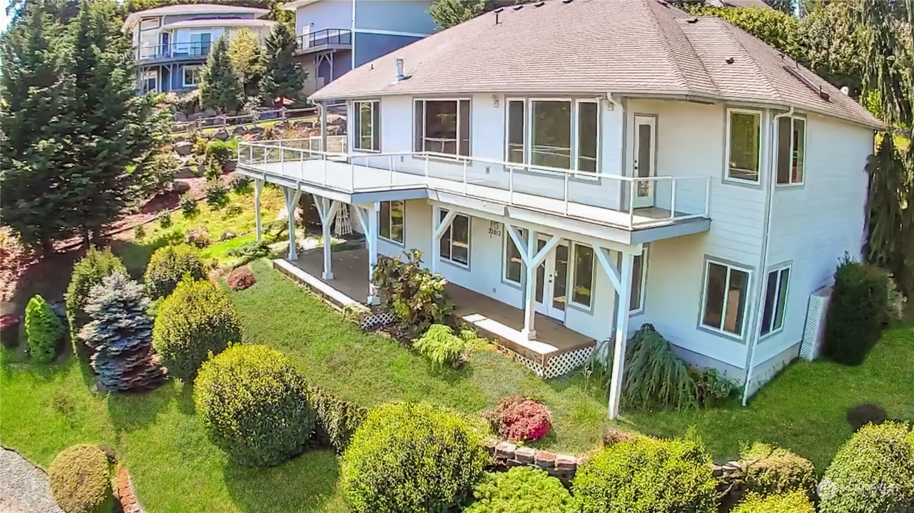 a front view of a house with a yard potted plants and large tree