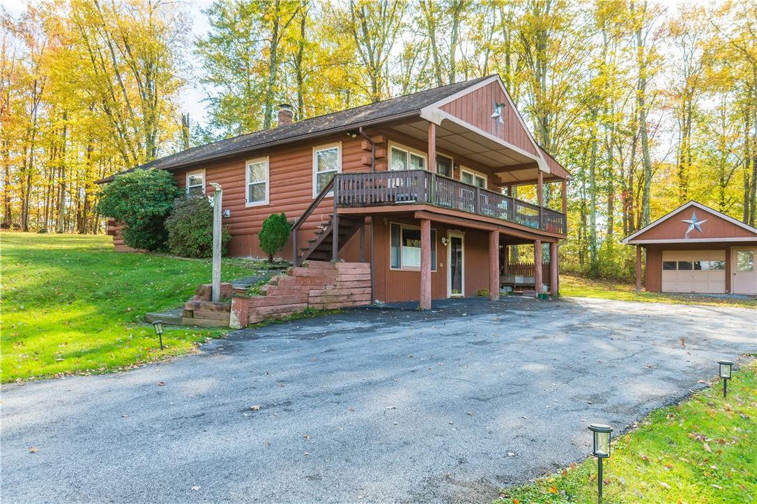 View of front of property with an outbuilding, a wooden deck, a front lawn, and a garage