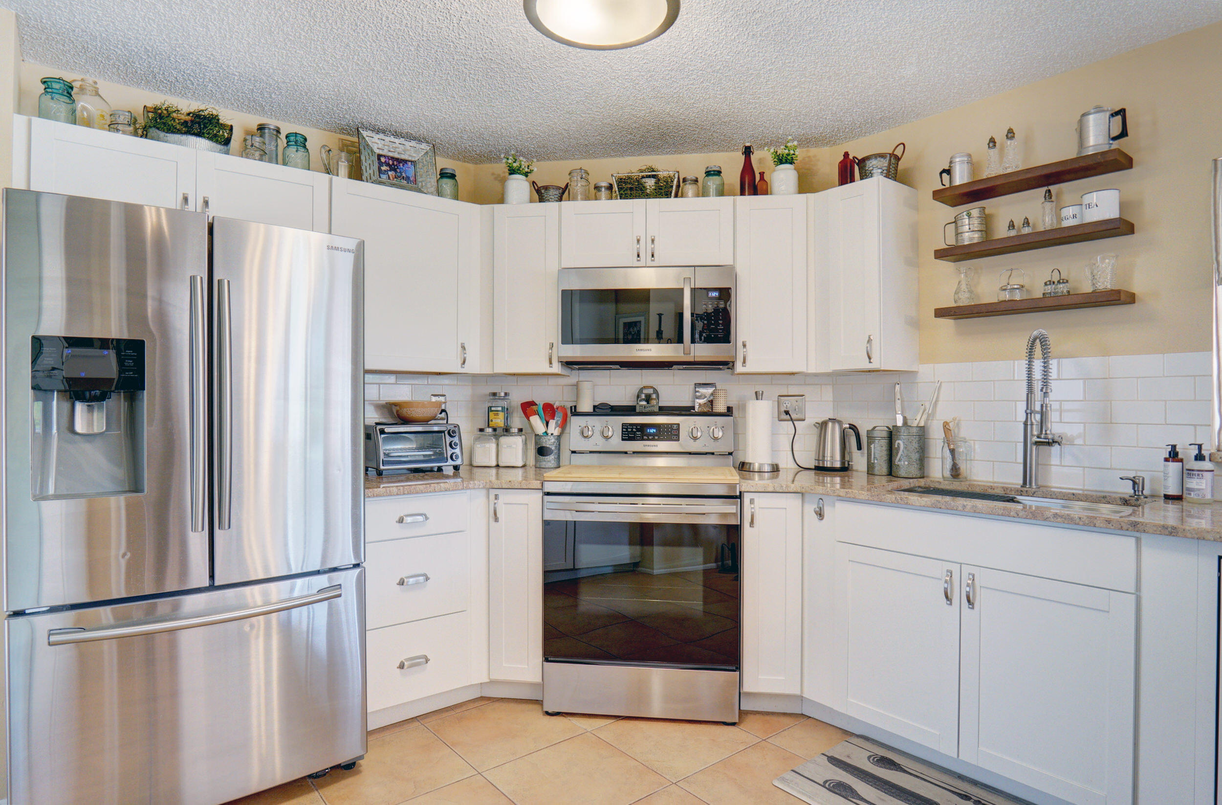 a kitchen with stainless steel appliances granite countertop a refrigerator sink stove and white cabinets