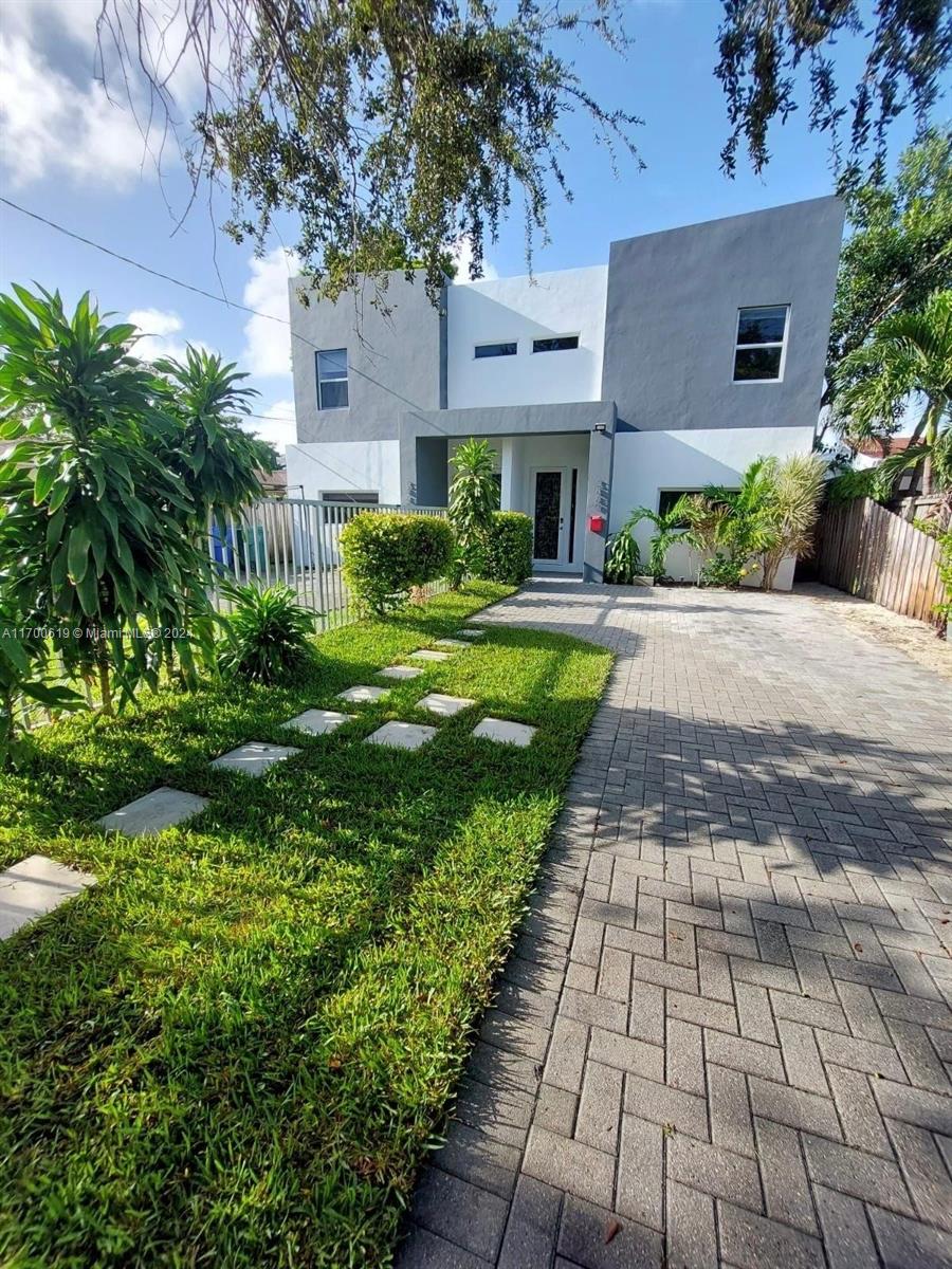 a front view of a house with a yard and potted plants