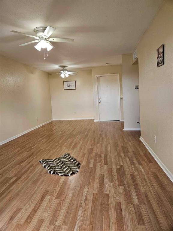 a view of a room with wooden floor and a ceiling fan