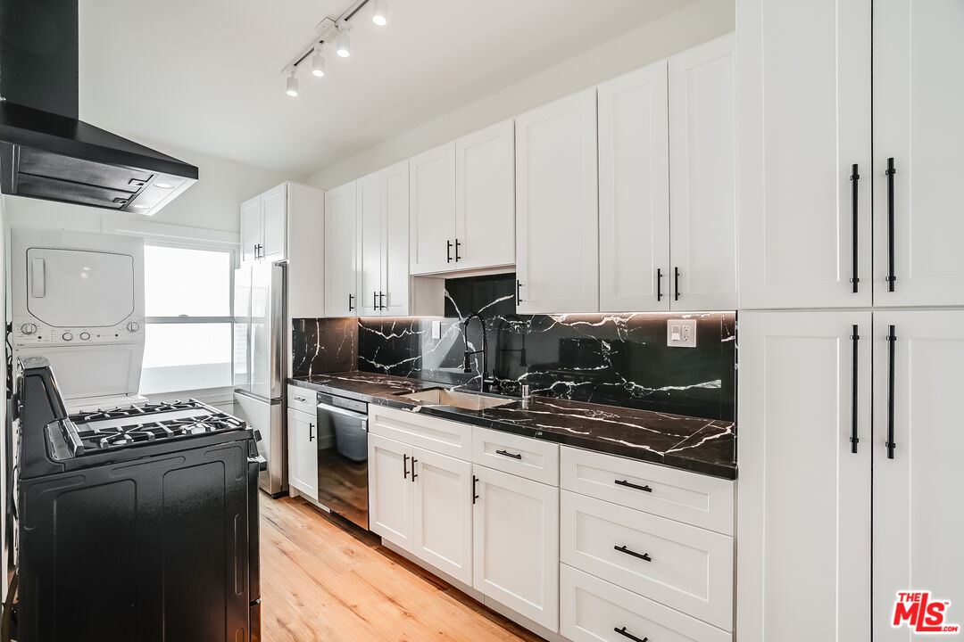 a kitchen with stainless steel appliances granite countertop a stove a refrigerator and a white cabinets