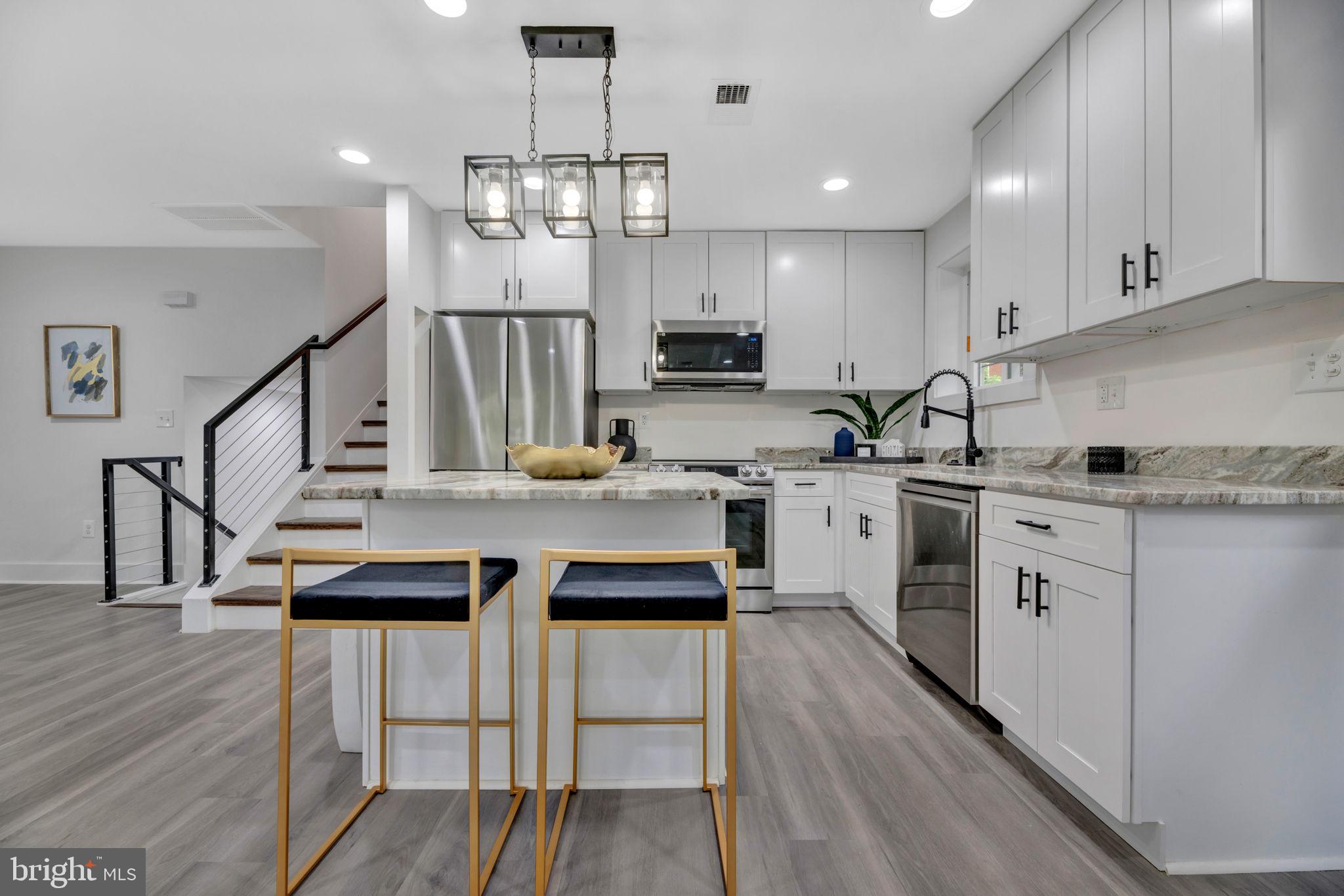 a kitchen with a sink a center island stainless steel appliances and cabinets