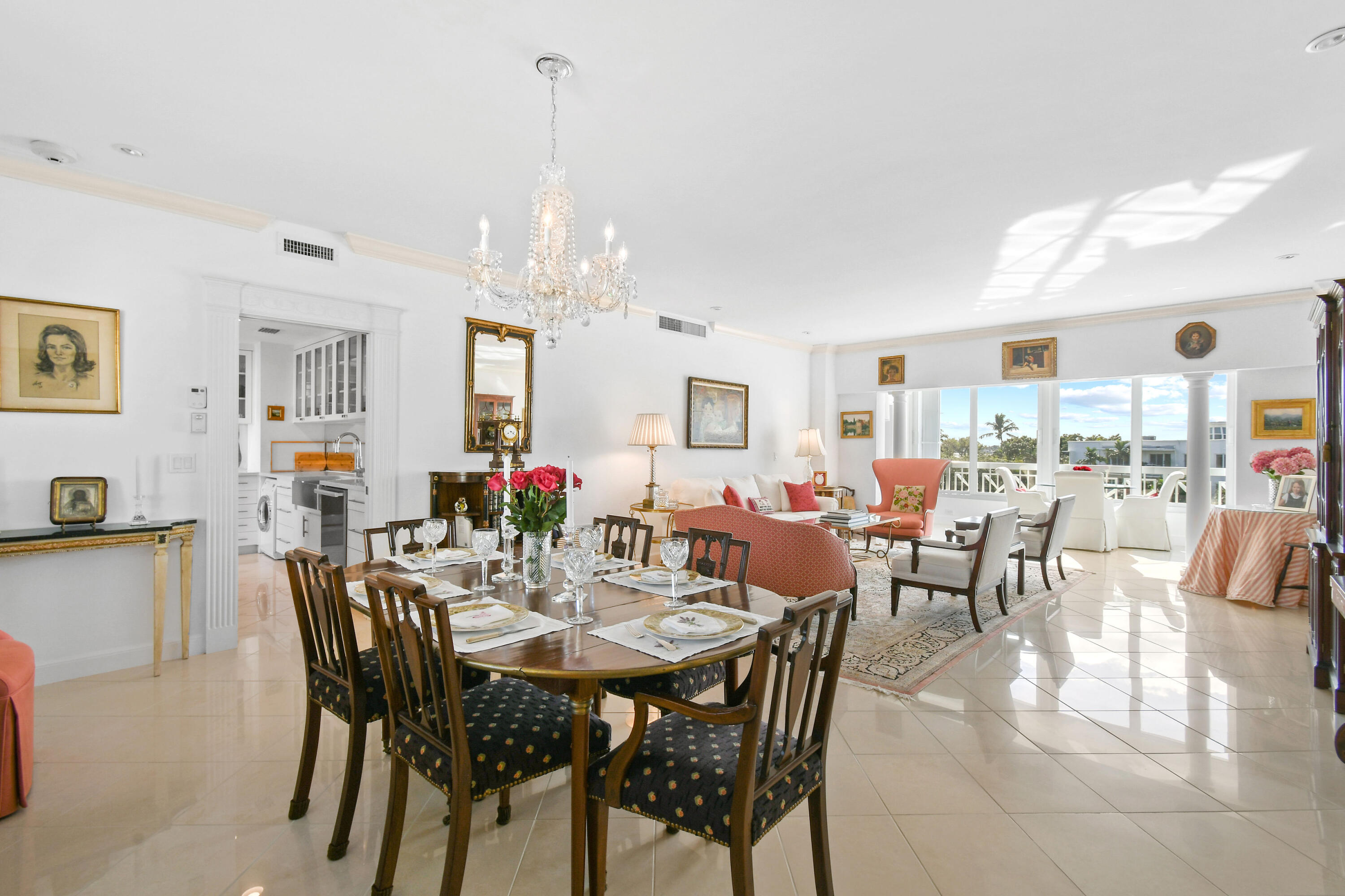 a view of a dining room and livingroom with furniture wooden floor a rug a painting and a chandelier