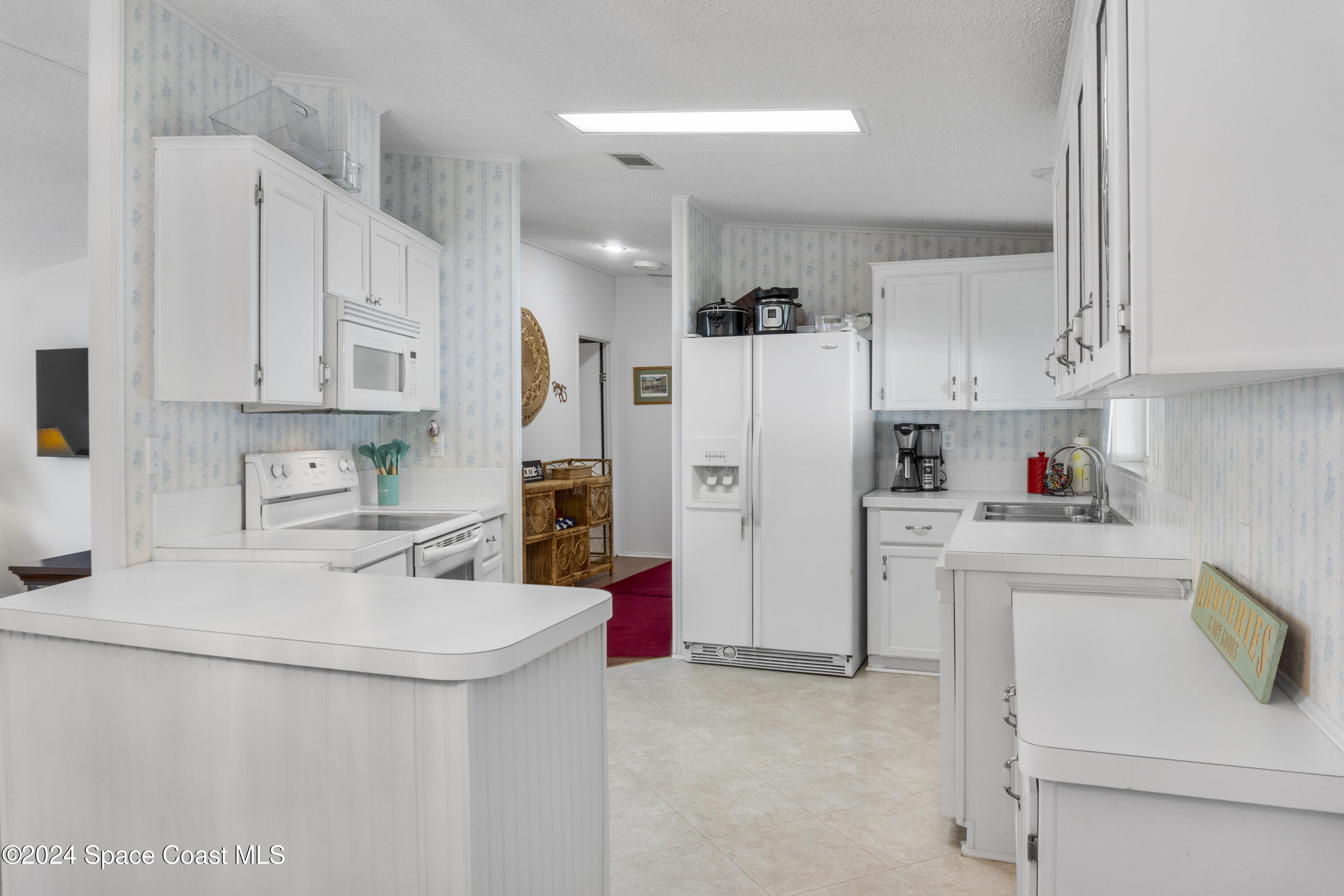 a kitchen with white cabinets and refrigerator