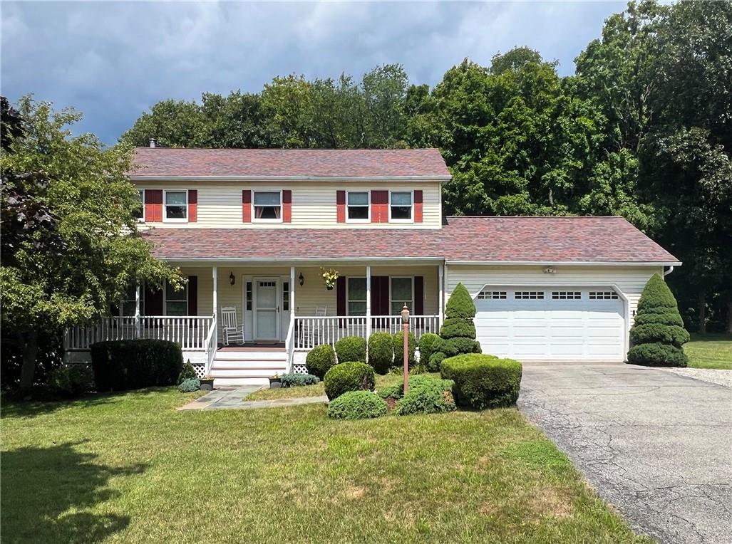 Colonial house with a front lawn, covered porch, and a garage