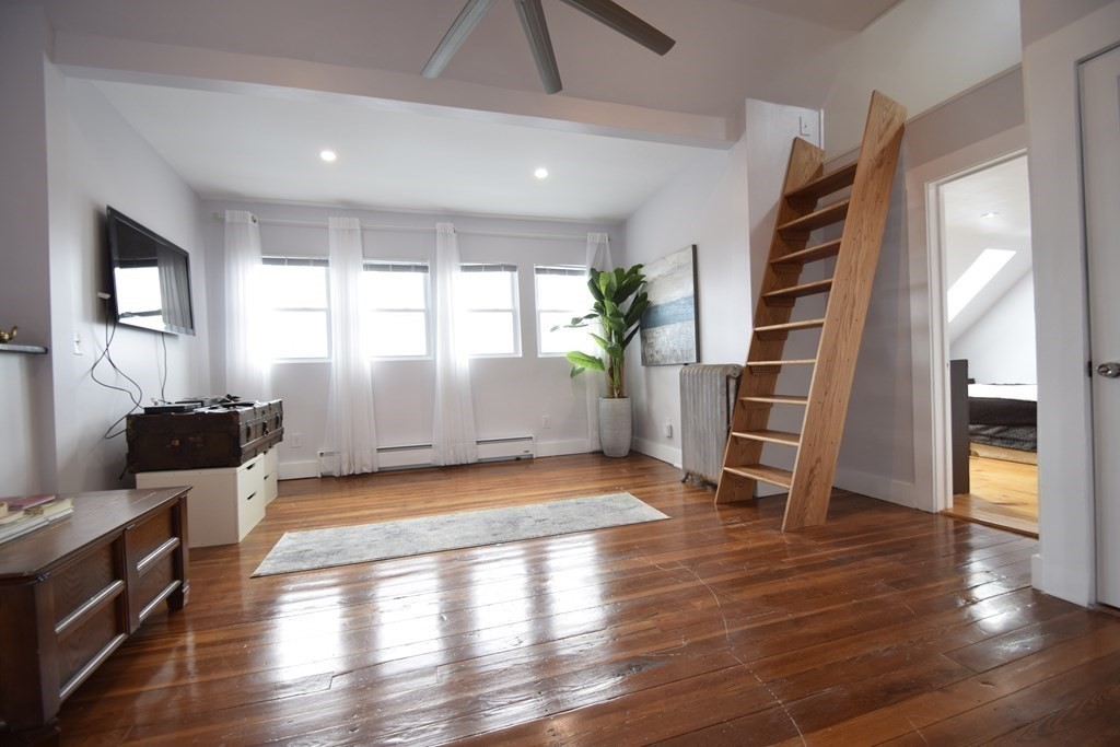 a view of empty room with wooden floor and fan