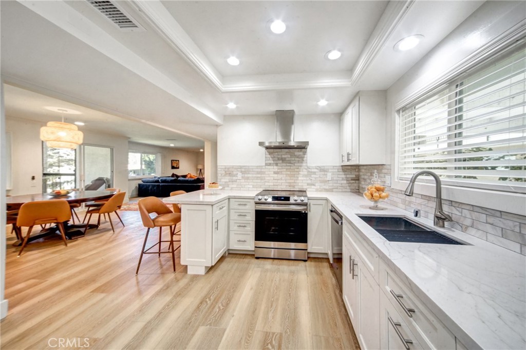 a kitchen with a sink stove a refrigerator and white cabinets next to a window