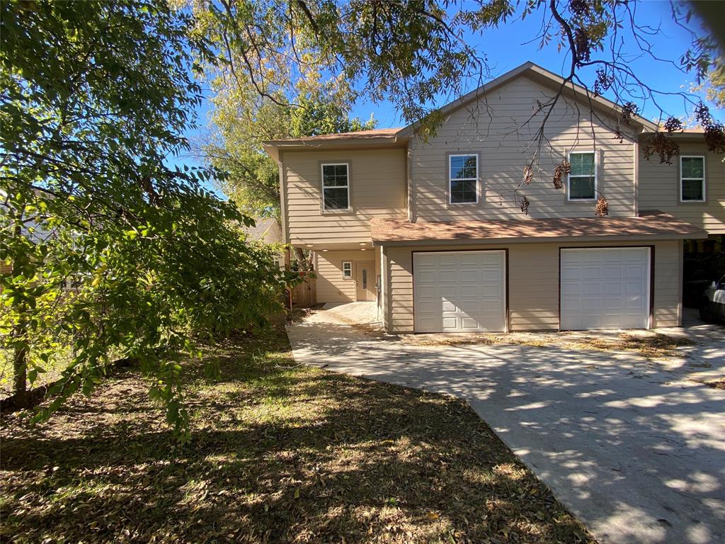 a front view of a house with yard garage and tree