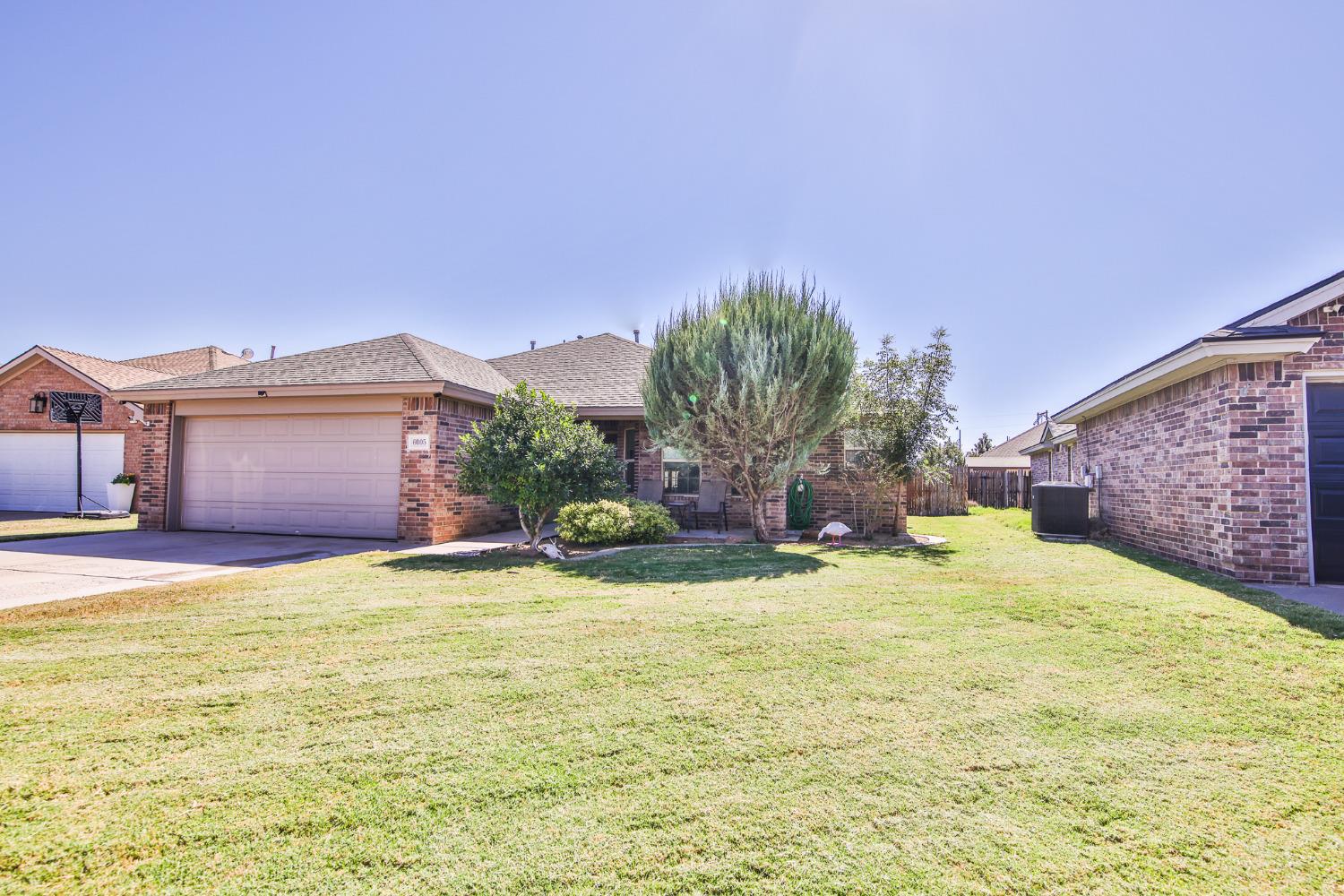 a view of a house with a yard and a large tree