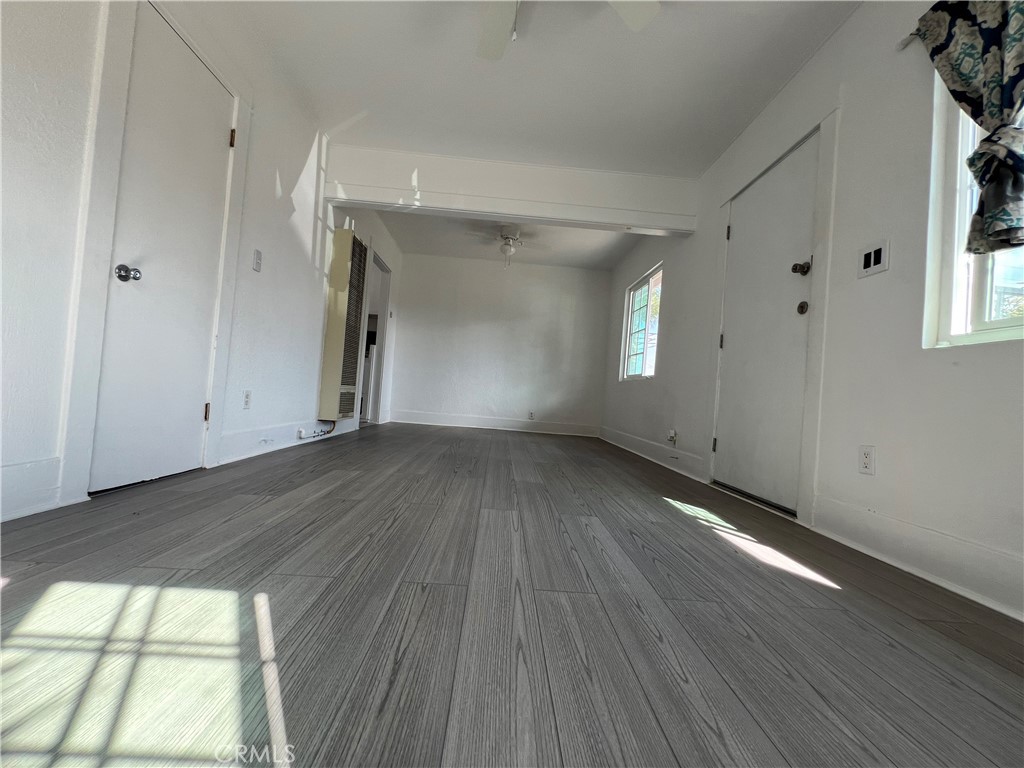 an empty room with wooden floor and windows