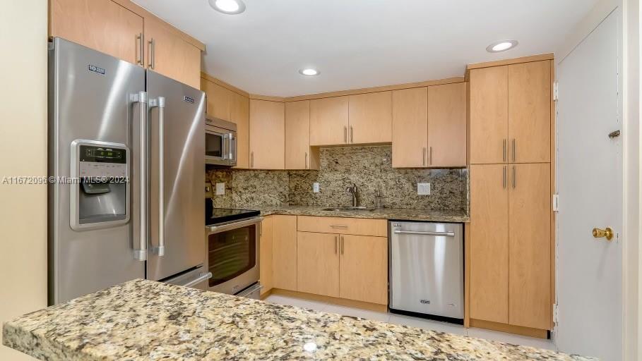 a kitchen with stainless steel appliances granite countertop a refrigerator a stove and a sink