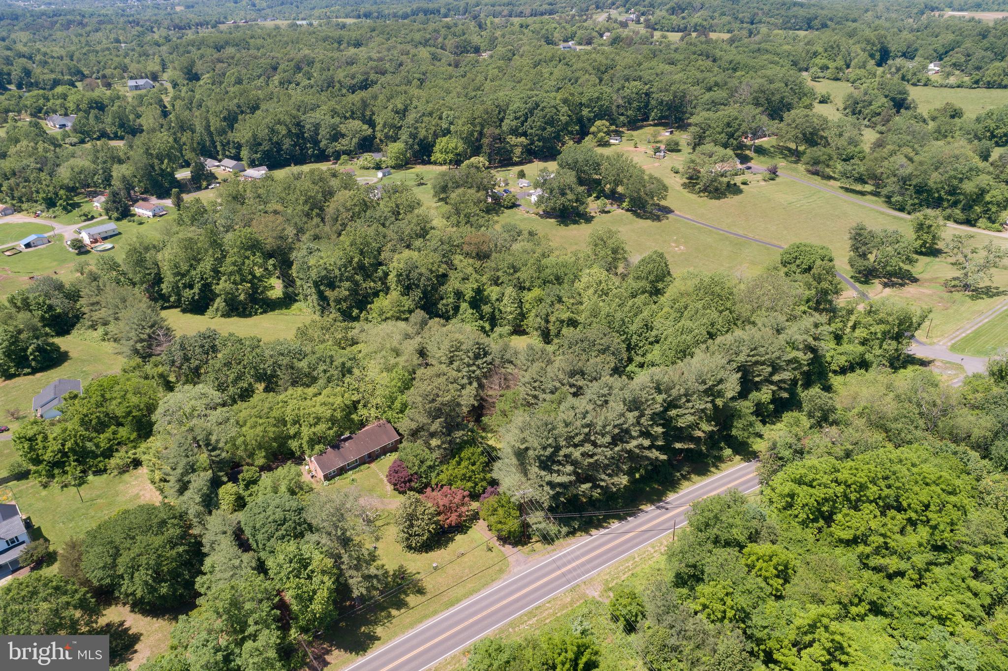 an aerial view of residential house with outdoor space and trees all around