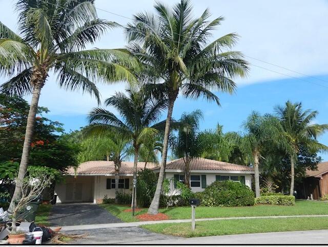 a view of a house with a yard and palm trees