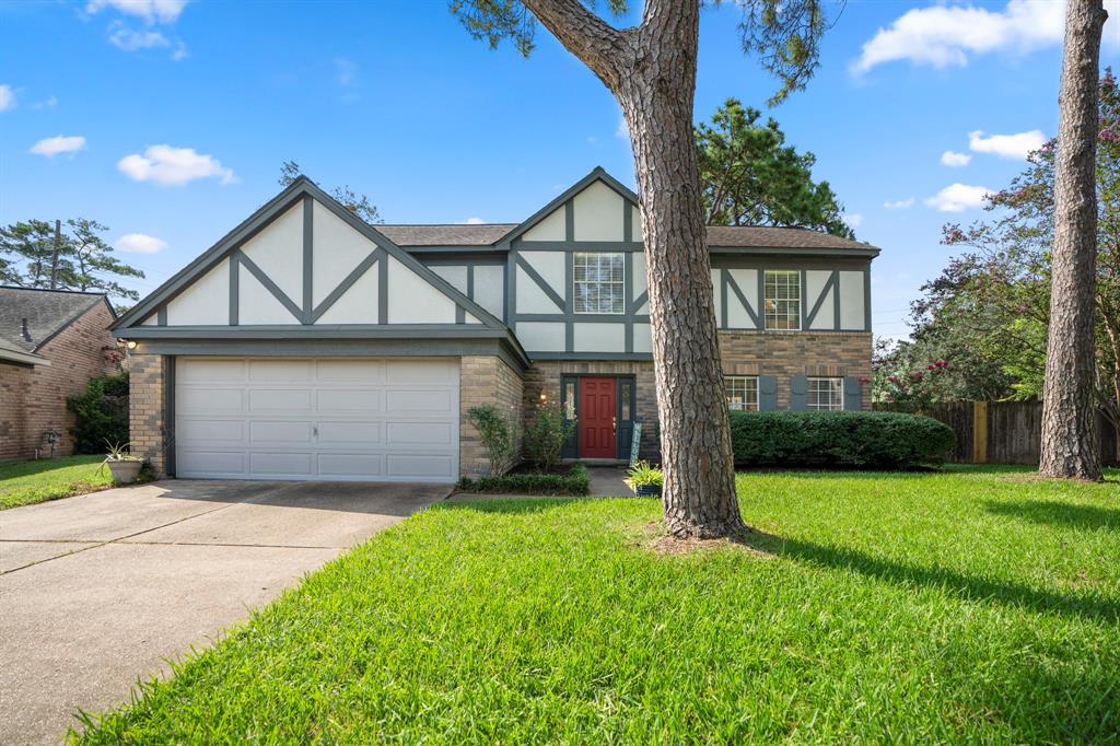 Charming Tudor-style home featuring a welcoming red door, contrasting trim, and well-maintained landscaping. The exterior brickwork adds a classic touch.