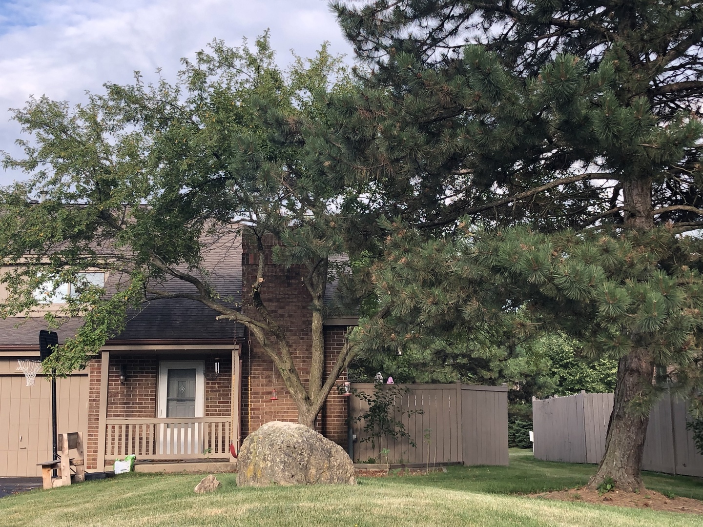 a view of a brick house with a big yard and large trees