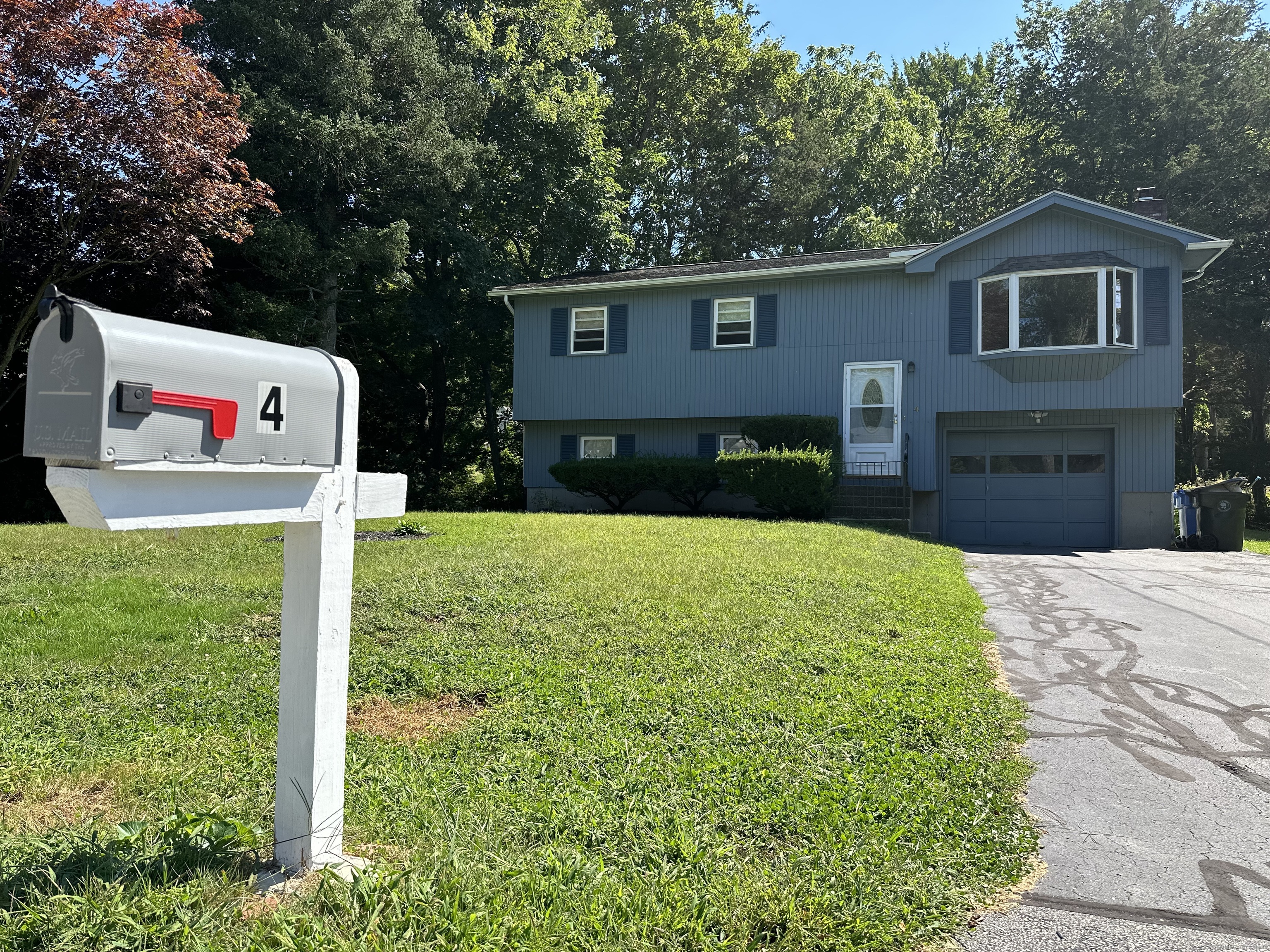 a sign that is sitting in front of a brick house with plants