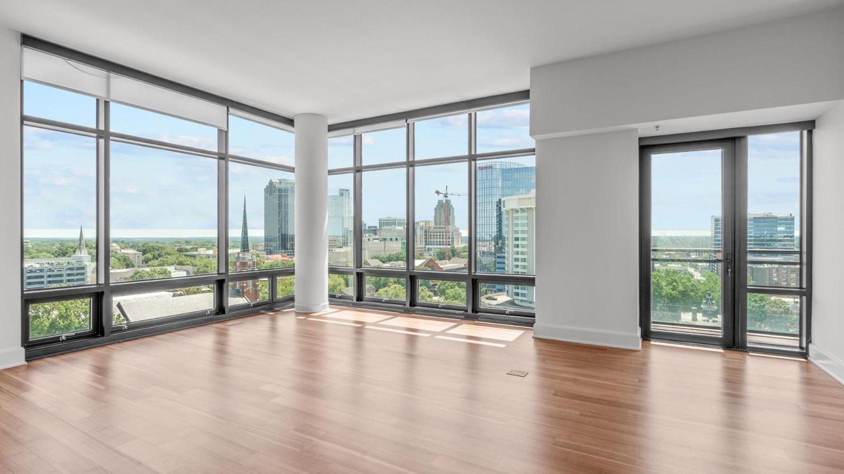 a view of empty room with wooden floor and floor to ceiling window