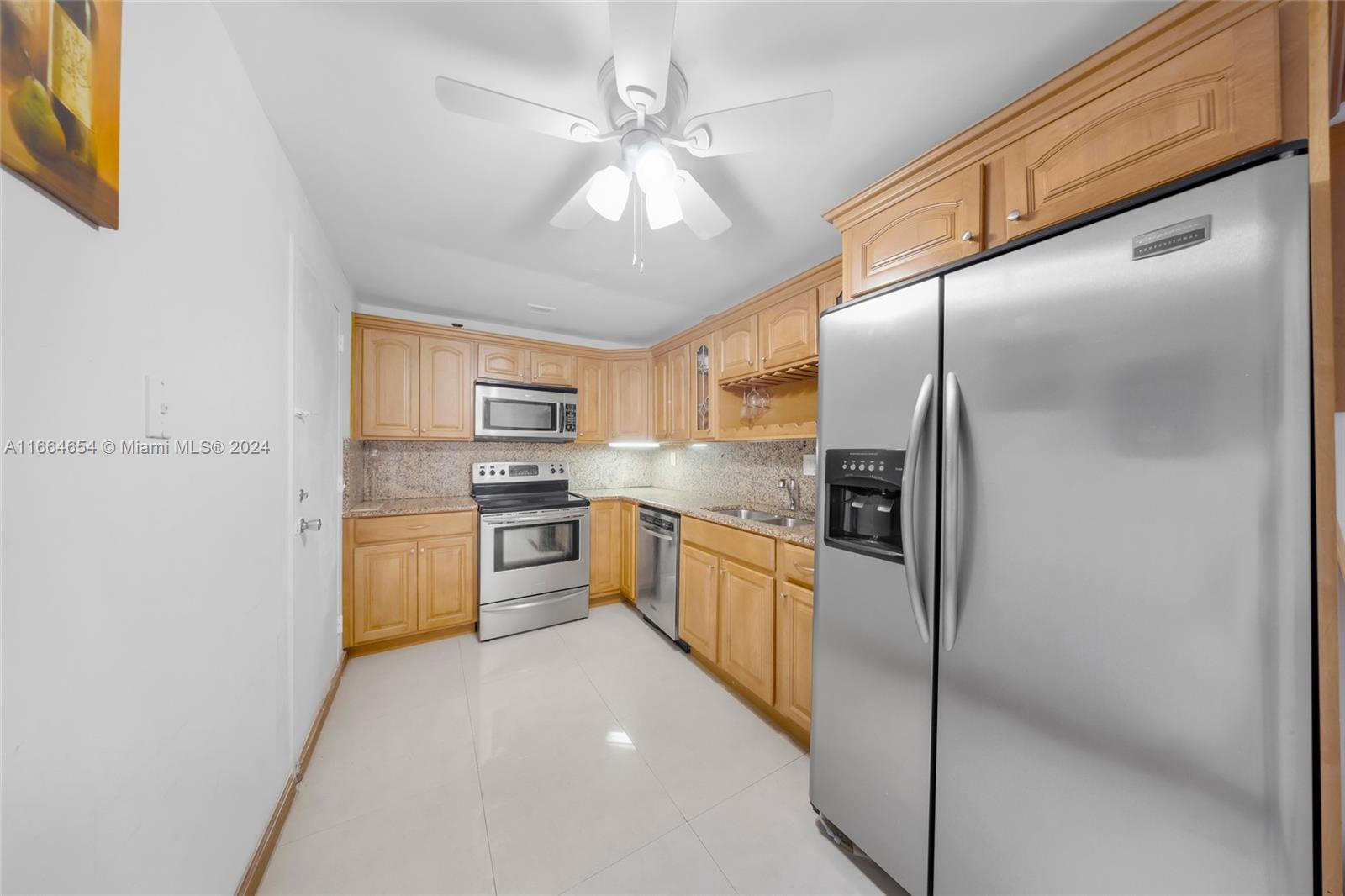 a large kitchen with cabinets a sink and stainless steel appliances