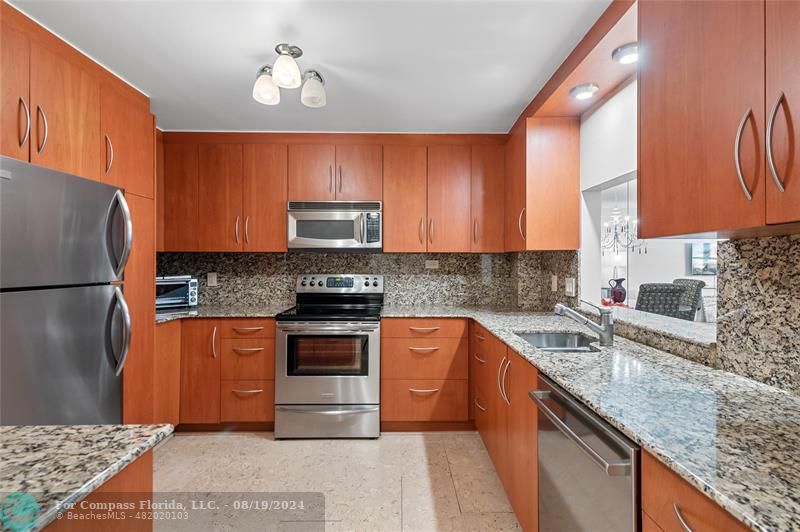 a kitchen with stainless steel appliances granite countertop a stove a sink dishwasher a refrigerator and a microwave