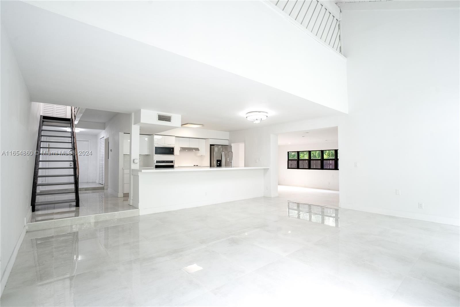 a view of a livingroom with kitchen and staircase