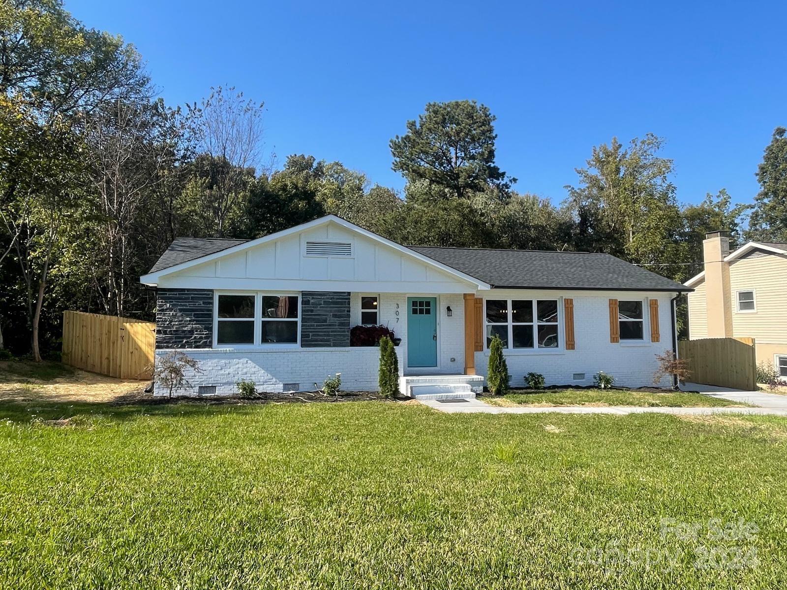 a front view of house with yard and trees in the background